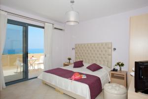 a bedroom with a bed and a balcony with the ocean at Carme Villas in Adelianos Kampos