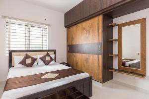 a bedroom with a large bed and a mirror at Olive Serviced Apartments HSR Layout in Bengaluru