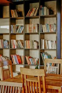 a table with two chairs in front of a shelf of books at Vēju Paradīze in Pāvilosta