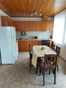 eine Küche mit einem Tisch und einem weißen Kühlschrank in der Unterkunft Вила Текето in Obrochishte