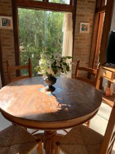 einem Holztisch mit einer Vase mit einer Pflanze darauf in der Unterkunft Guest House Tânia Alves in Pratinha