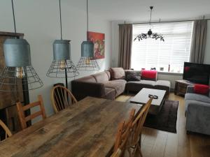 ein Wohnzimmer mit einem Tisch und einem Sofa in der Unterkunft Woning Emmastraat in Katwijk aan Zee