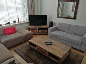 ein Wohnzimmer mit 2 Sofas und einem TV in der Unterkunft Woning Emmastraat in Katwijk aan Zee