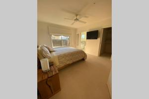 um quarto com uma cama e uma ventoinha de tecto em Sun-lovers Beach House - Walk to beach/shops! em Rosebud