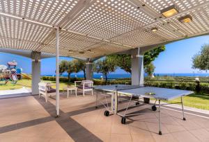 un patio con una mesa de ping pong bajo una pérgola en Carme Villas, en Adelianos Kampos