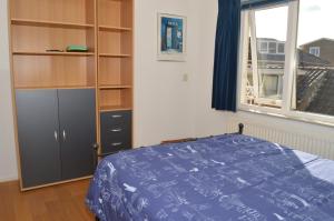 ein Schlafzimmer mit einem Bett und einem Bücherregal in der Unterkunft Woning Emmastraat in Katwijk aan Zee