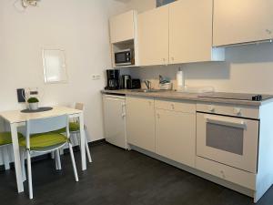 - une cuisine avec des placards blancs, une table, une table et des chaises dans l'établissement Appartement im Herzen von Leimen, à Leimen