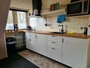 a kitchen with white cabinets and a microwave at Appartement Schoorl in Schoorl