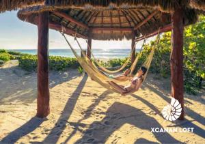 a man laying in a hammock on a beach at Xcanan Loft On Park Royal, the best area in Cancún right on the beach in Cancún