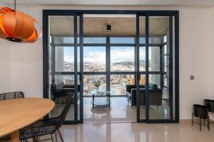 sala de estar con mesa, sillas y puertas de cristal en HomeForGuest NEW Modern Penthouse Apartment with panoramic views of Santa Cruz, en Santa Cruz de Tenerife