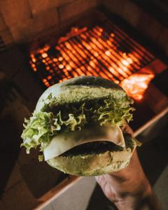 a person holding a sandwich in front of a grill at Seven Elements Resort in Ras al Khaimah