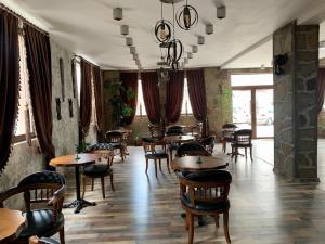 a restaurant with wooden tables and chairs and windows at Grand Altunhan Hotel in Svilengrad