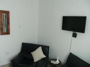 a living room with a black couch and a flat screen tv at Casa Bianco in Montagu