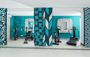 a gym with blue walls and mirrors and tread machines at Hotel Della Piccola Marina in Capri
