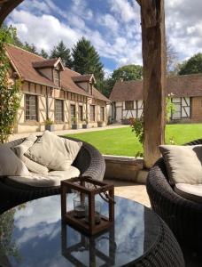 een patio met rieten meubels en een glazen tafel bij Le pigeonnier de la Farge in Chaumont-sur-Tharonne