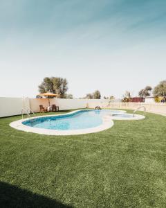 a swimming pool in a yard with grass at Seven Elements Resort in Ras al Khaimah