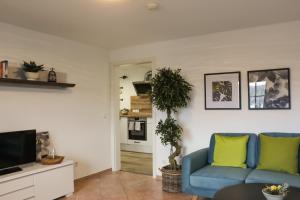 a living room with a blue couch and a tv at Haus Emmerich in Gaienhofen