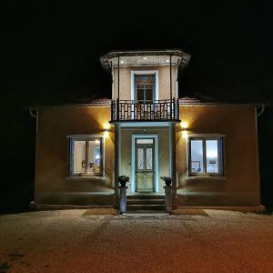 ein Haus mit einem Balkon und einer Tür in der Nacht in der Unterkunft La Maison Fleur de Frangipanier in Saint-Genix-sur-Guiers