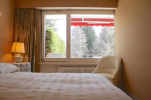 ein Schlafzimmer mit einem Fenster mit einem Bett und einem Stuhl in der Unterkunft Spacious with Garden for up to 6 guests, Mamounia in Crans-Montana