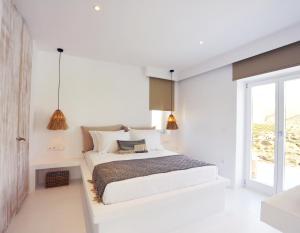 a white bedroom with a bed and a window at Pili Pala Suites in Episkopianá