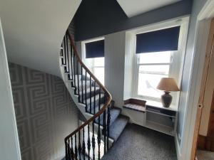 a hallway with a staircase with a lamp and a window at House by the Harbour - NC500 Route in Wick