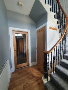 a hallway with a staircase and a door at House by the Harbour - NC500 Route in Wick