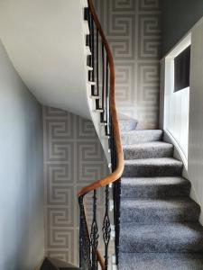 a stairwell with a wooden rail and a staircase with grey carpet at House by the Harbour - NC500 Route in Wick