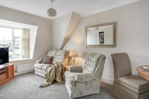een woonkamer met 2 stoelen en een televisie bij The Chesterfield Guest House, Torquay in Torquay