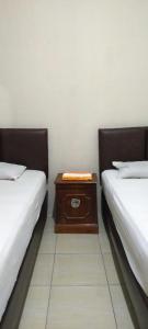 two beds in a room with a table between them at Aqsa Guest House Banjarsari 