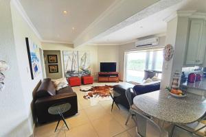 a living room with a couch and a table at Uvongo - Beach Paradise & Open Ocean View in Uvongo Beach