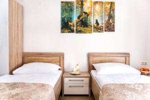 two beds in a room with paintings on the wall at Apartments Davydov in Bad Hofgastein