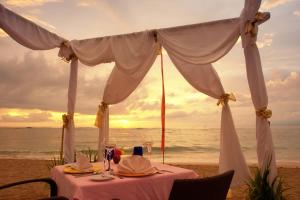 a dinner table on the beach with the sunset at Pool Villa Merumatta Senggigi in Senggigi