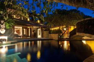 a house with a swimming pool at night at Pool Villa Merumatta Senggigi in Senggigi