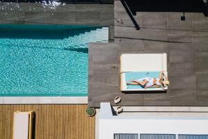 a woman laying in a chair next to a swimming pool at Artemisia Residence in Chania