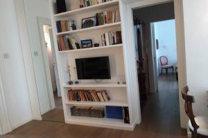una estantería de libros blancos con TV y libros en Casadianna, en Milán