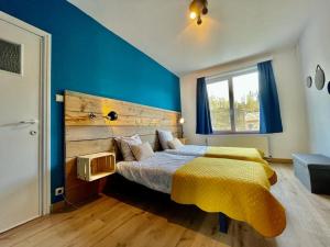 een slaapkamer met blauwe muren en een bed met een gele deken bij SOALLAROCHE in La-Roche-en-Ardenne