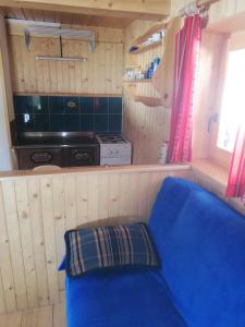 a blue couch in a kitchen with a stove at Brunarica na Goreljeku in Bohinj