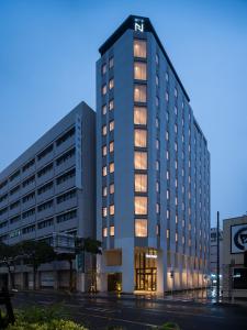 un edificio blanco alto con luces encendidas en Nest Hotel Naha Kumoji en Naha