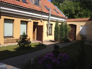 a house with a yard with purple flowers in front of it at Gallery Balta Apartments in Kaunas