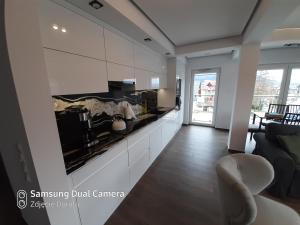 Apartament Mszana Dolna في مشانا دولنا: غرفة معيشة مع مطبخ مع دواليب بيضاء
