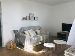 a living room with a couch and two tables and a tv at Casa da Ilha in Madalena