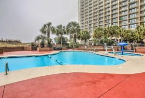
a pool with a pool table and chairs in front of a building at Beachfront Resort Condo with Lazy River and Pools! in Myrtle Beach
