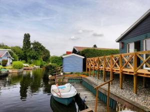 a small boat is docked next to a house at Ferienhaus Grosses Meer mit Boot in Südbrookmerland