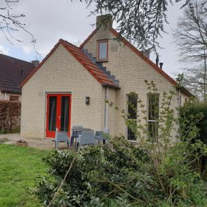 una casa di mattoni bianchi con una porta rossa di Gezellige vakantiewoning met sauna in Ewijk bij Nijmegen - recreational only no workers a Ewijk