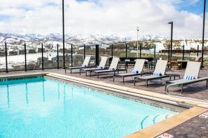 a swimming pool with lounge chairs and snow covered mountains at Black Rock Mountain Resort in Park City
