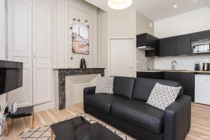 sala de estar con sofá negro y cocina en LE DANDY - T2 CENTRE HISTORIQUE en Agen