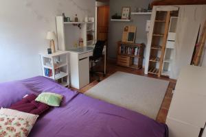 マルセイユにあるMaison avec jardin sur une collineの紫色のベッドとデスクが備わるベッドルーム1室が備わります。