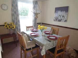 a dining room with a table with chairs and a table and a table and chairs at 2 Bed Cottage Dog Child Friendly 15min walk to beach in Ederyn