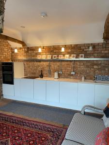 uma cozinha com armários brancos e uma parede de tijolos em The Green House em Horncastle