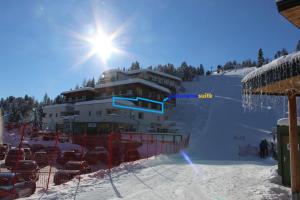 a building on a ski slope with the sun behind it at panoramasuite Turracherhöhe in Turracher Hohe